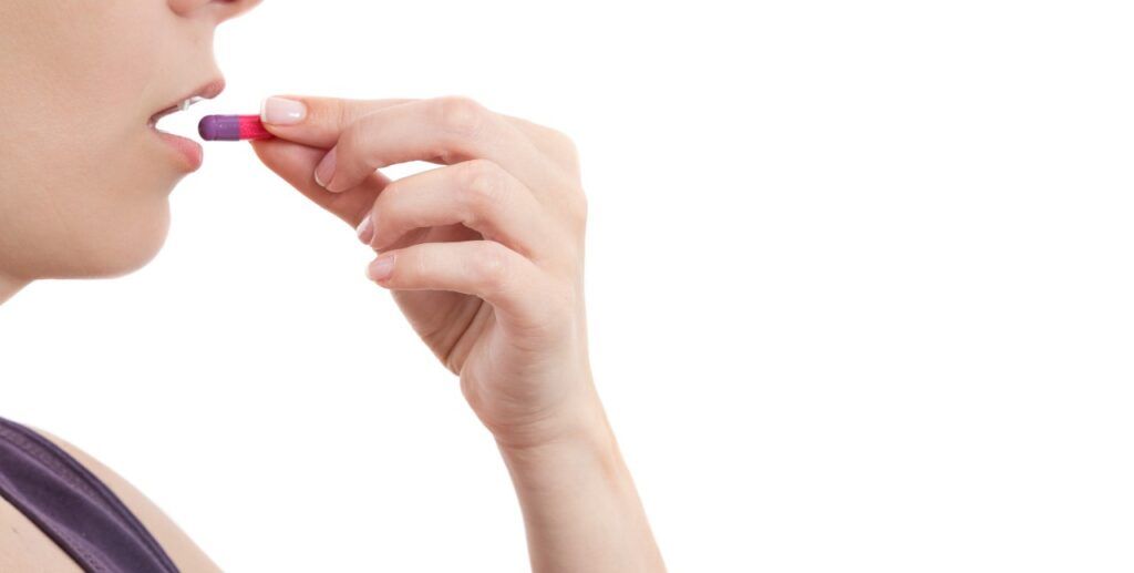 woman taking pill over white background