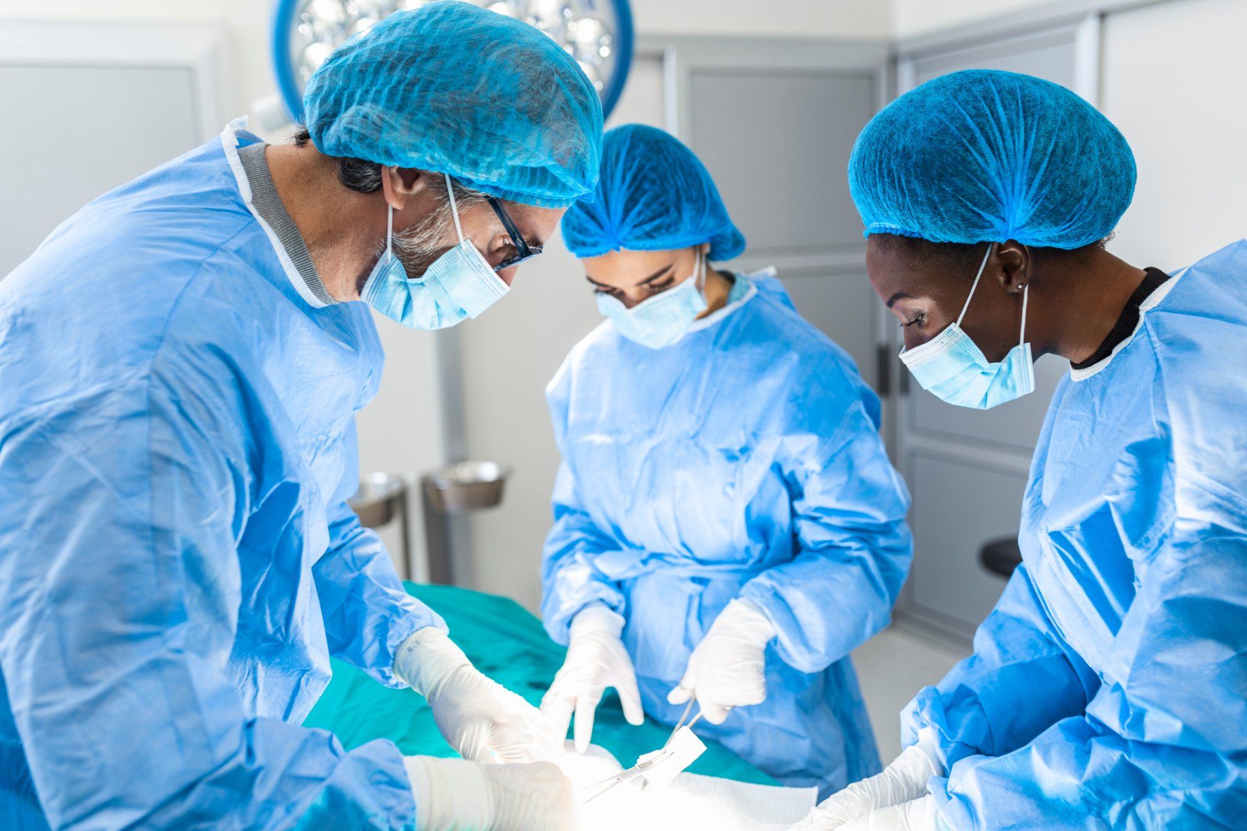 A surgical team in blue scrubs works on a patient - 3M Bair Hugger Class Action Lawsuit