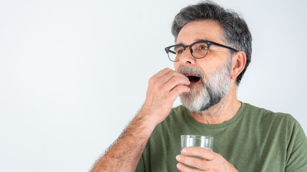 man with glass of water taking pill