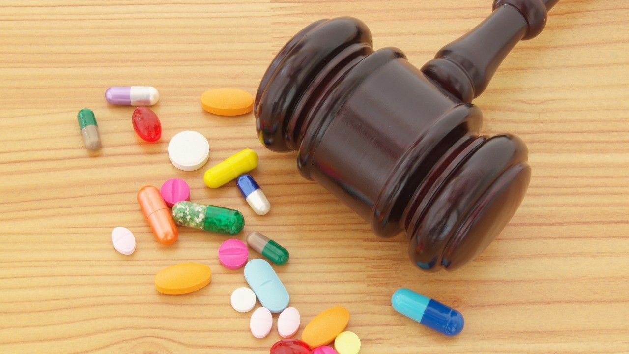 Wooden judge gavel with pharmaceutical drugs on table